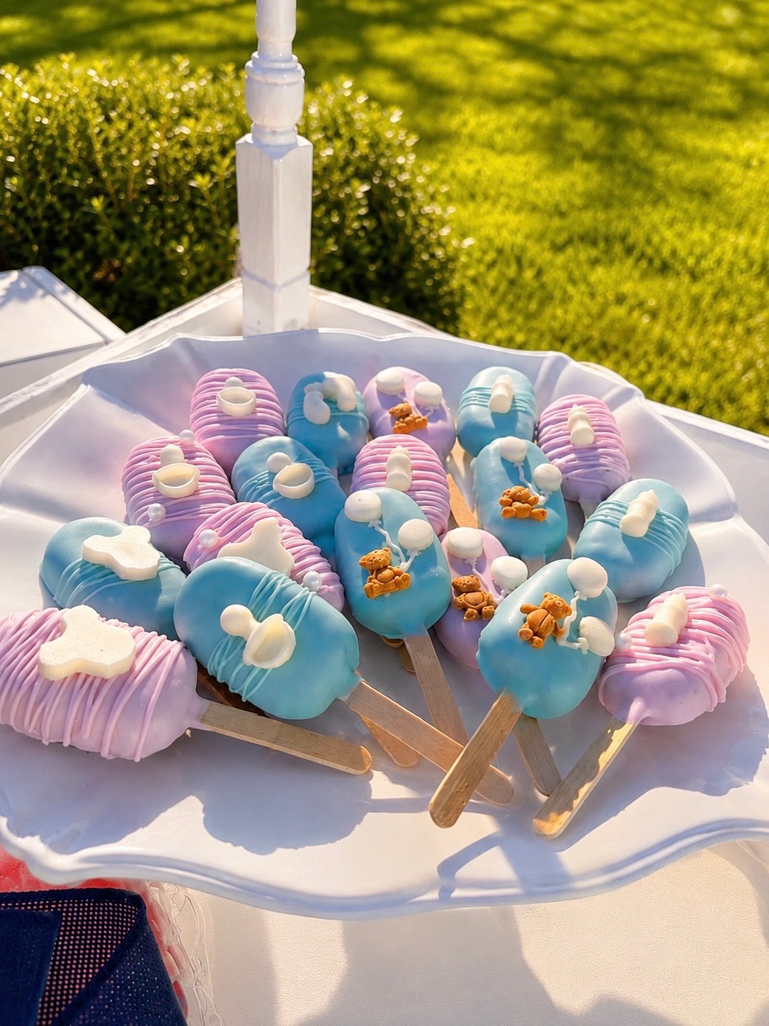 Pastel baby shower cakesicles on a scalloped plate